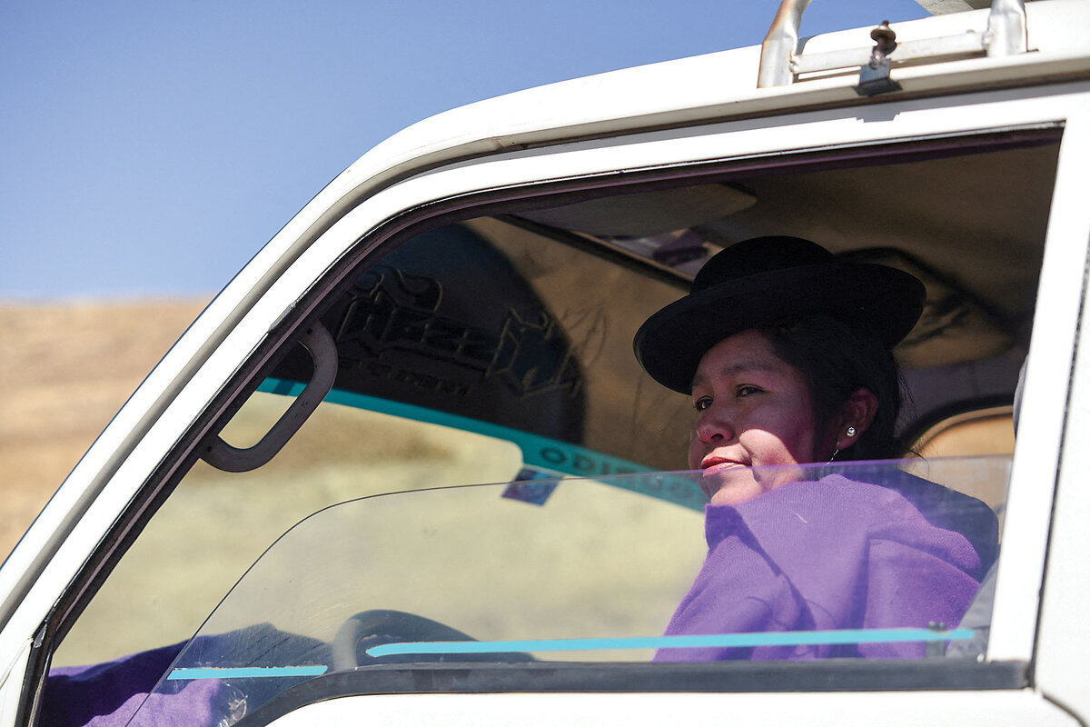 Felicidad Quispe, wearing a traditional black bowler hat, sits in her taxi in El Alto, Bolivia.