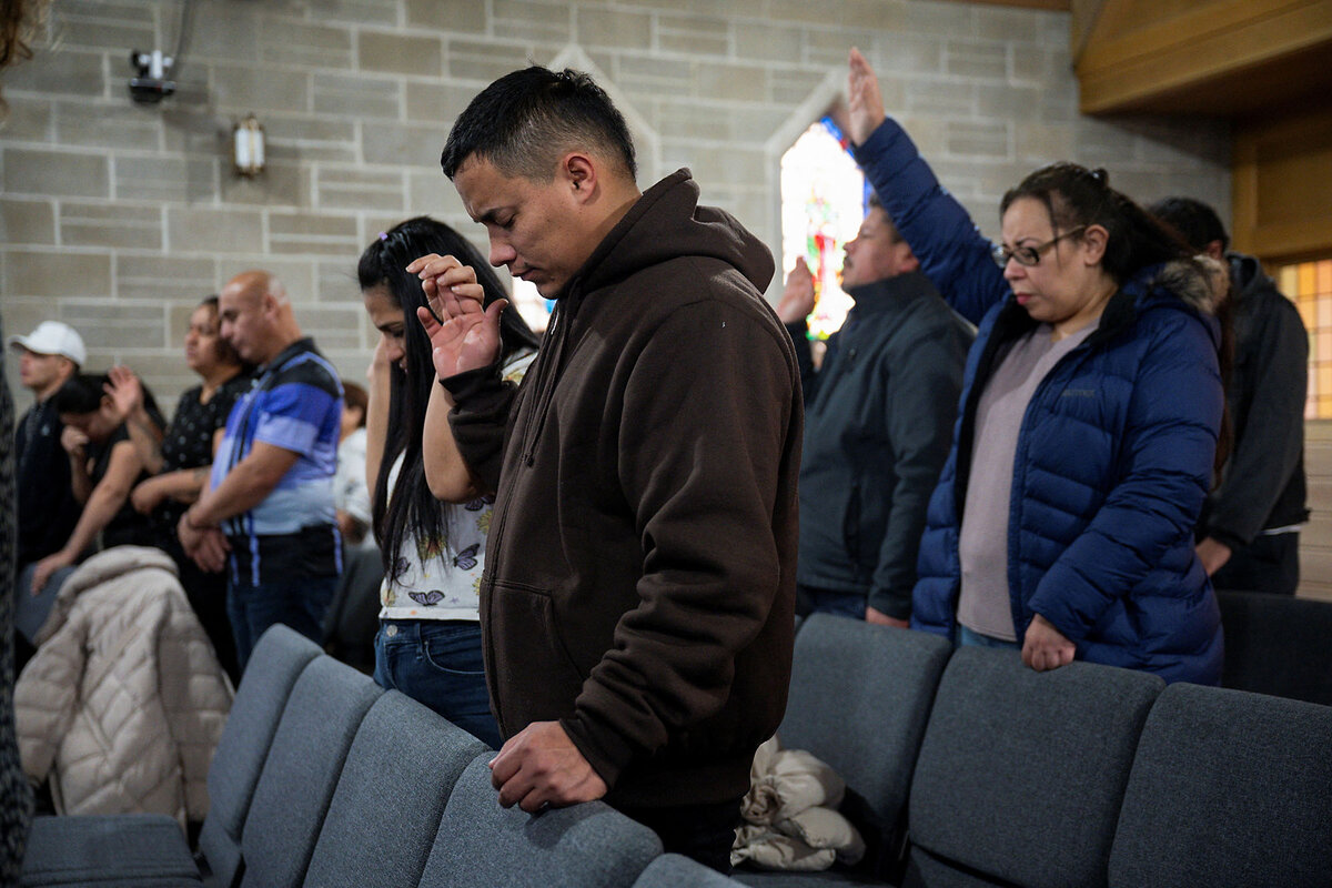 People bow their heads and raise their hands in prayer at Starting Point Community Church in Chicago.