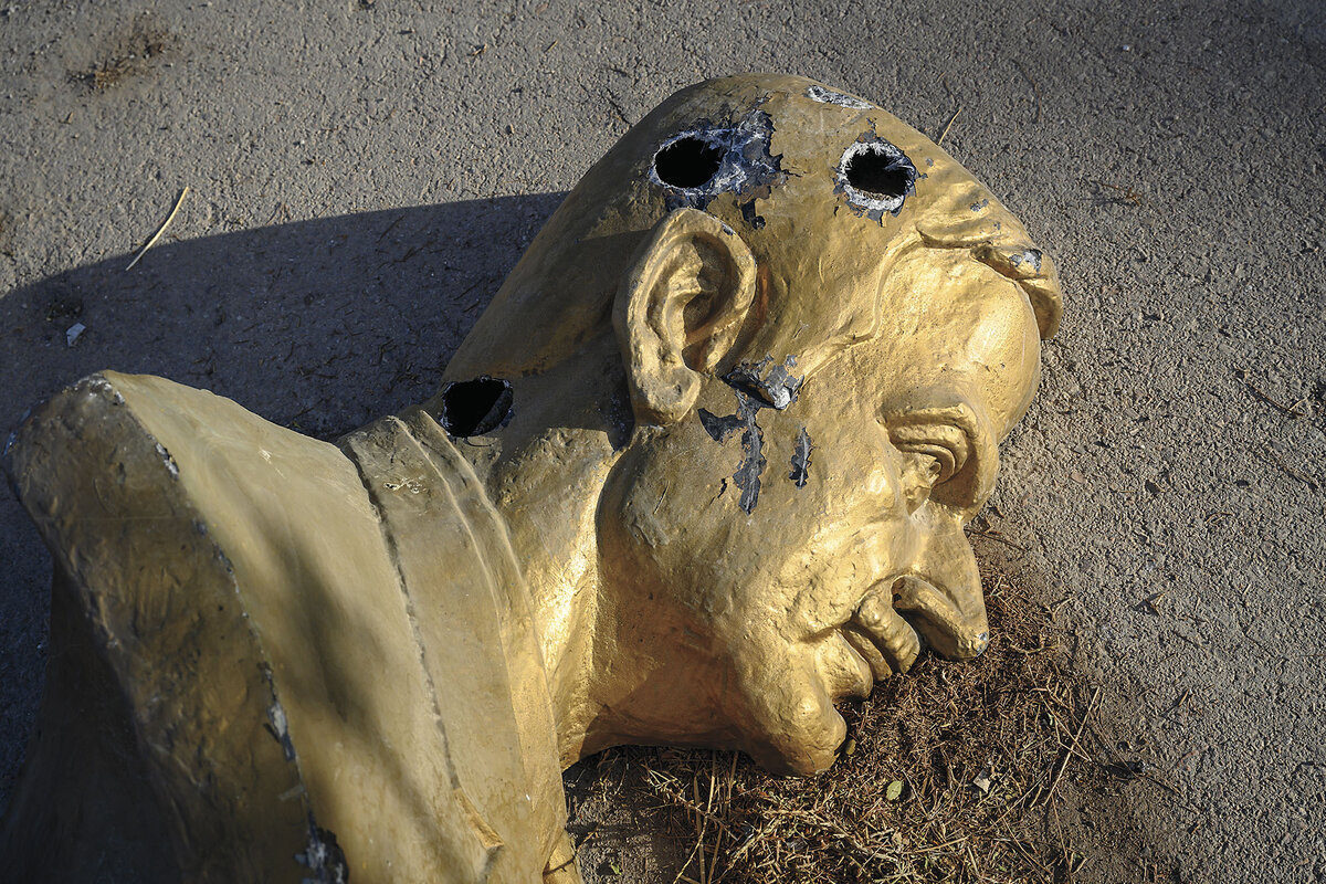 A bust of former Syrian President Hafez al-Assad lies on its side on concrete.