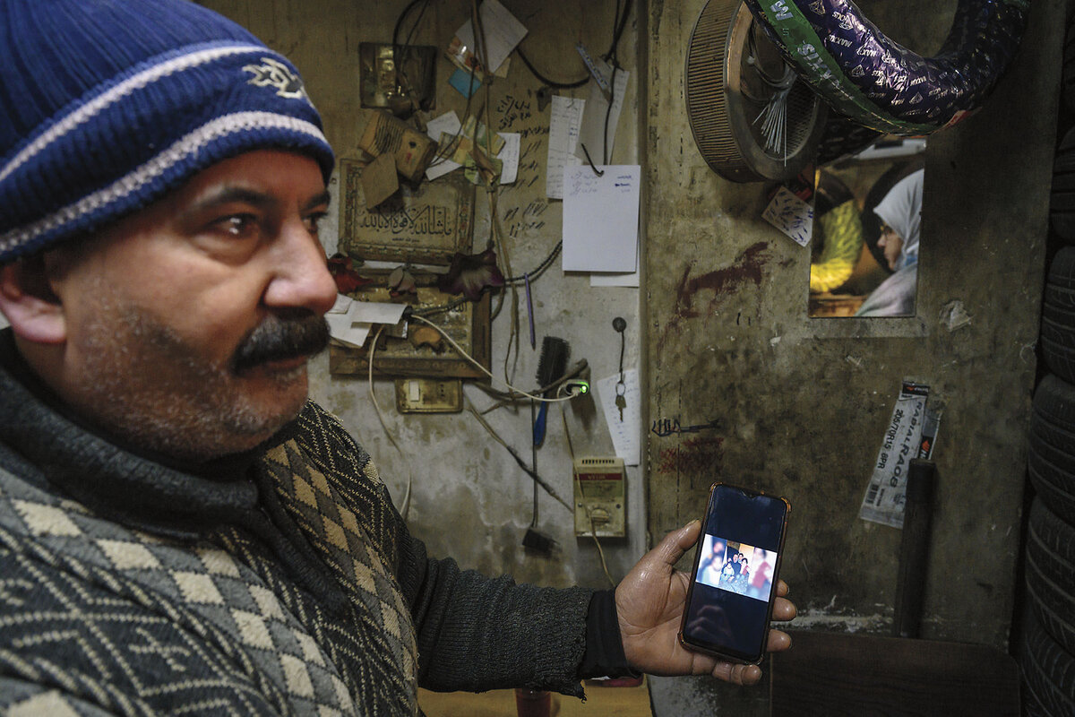 A Syrian man holds up a cellphone showing a photo of his lost family members.