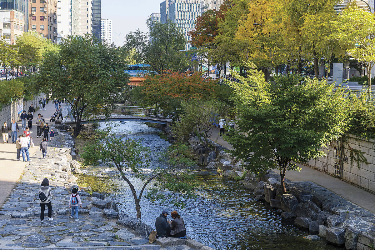 People walk along the paved banks of Cheonggyecheon, a 6 ½-mile-long stream and public space in downtown Seoul, South Korea. 