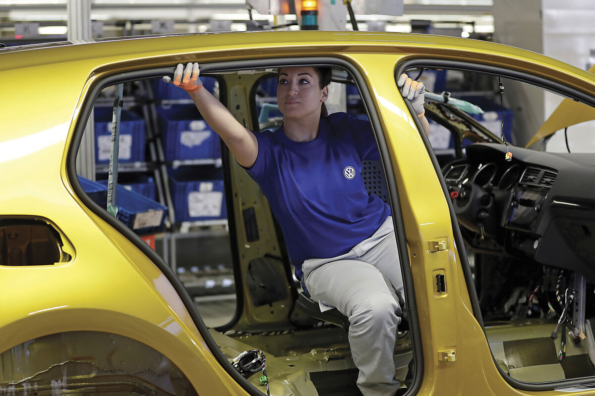 A Volkswagen worker sits inside the frame of a car making adjustments, in Wolfsburg, Germany.