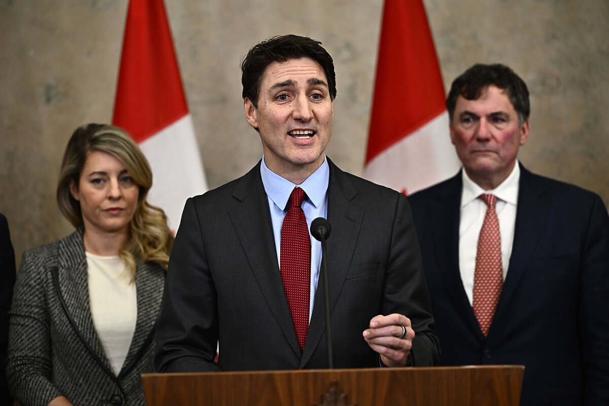 Justin Trudeau, wearing a dark suit, speaks to reporters from a podium.