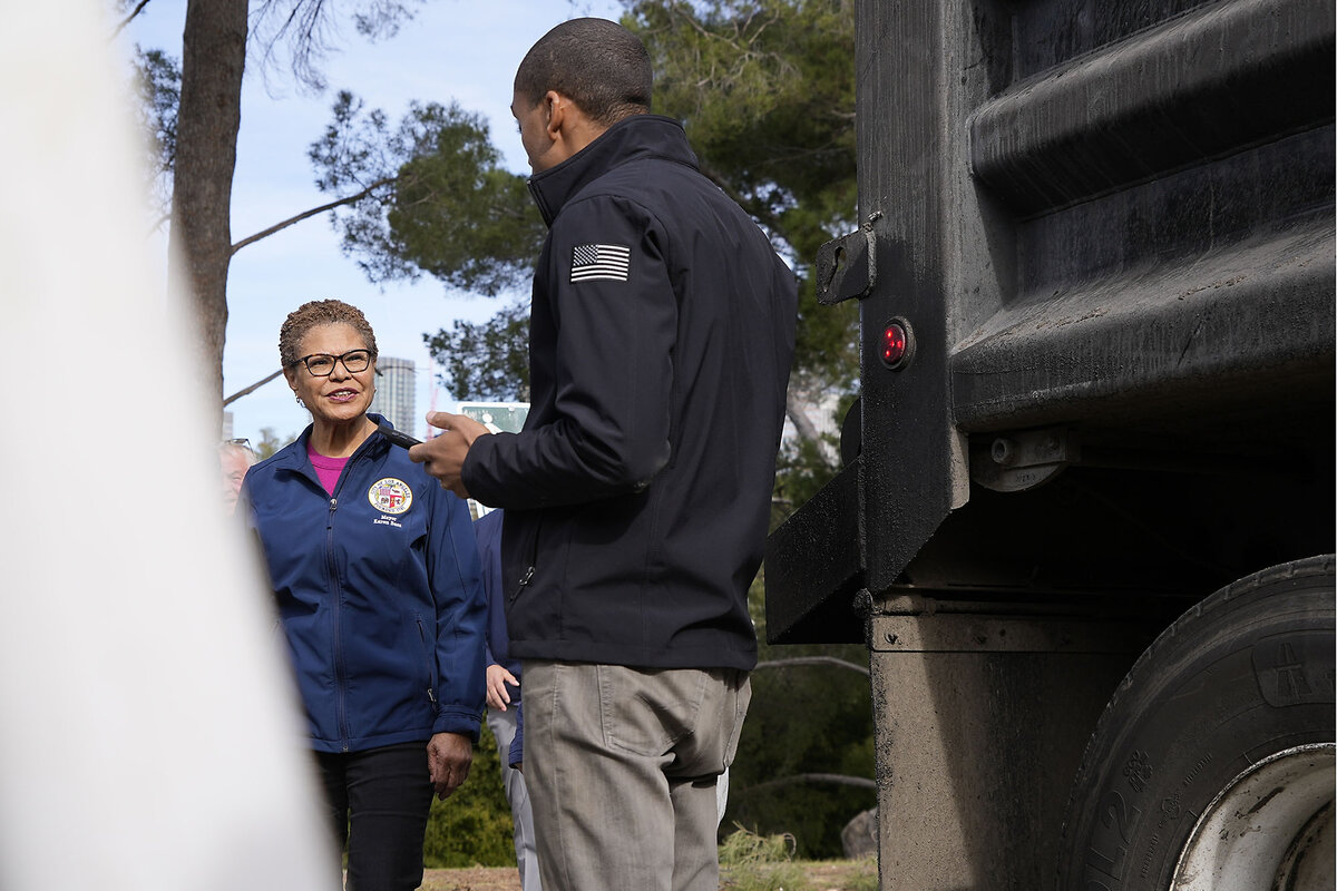 Los Angeles Mayor Karen Bass stands near a truck and talks with a city worker who is helping with LA's fire response.
