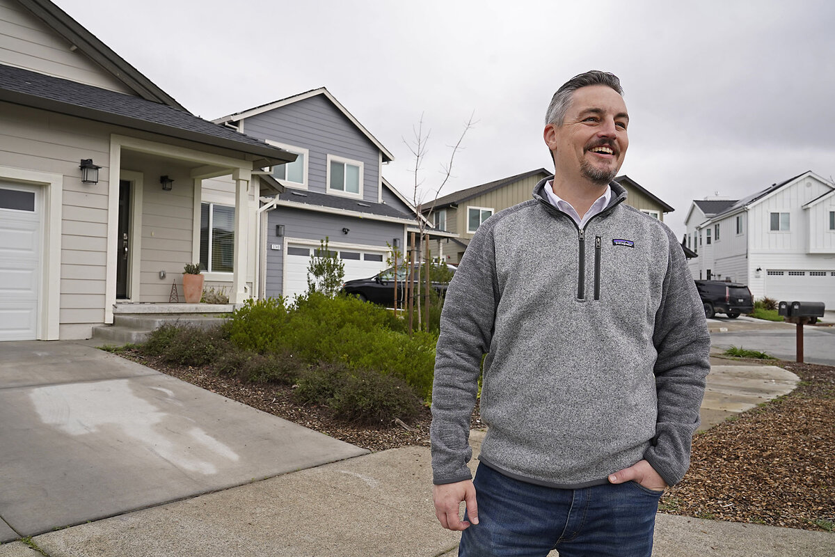 Jeff Okrepkie, wearing a gray sweatshirt and bluejeans, smiles as he stands in the driveway of his home in Santa Rosa, California. The home was rebuilt following wildfires there in 2017.