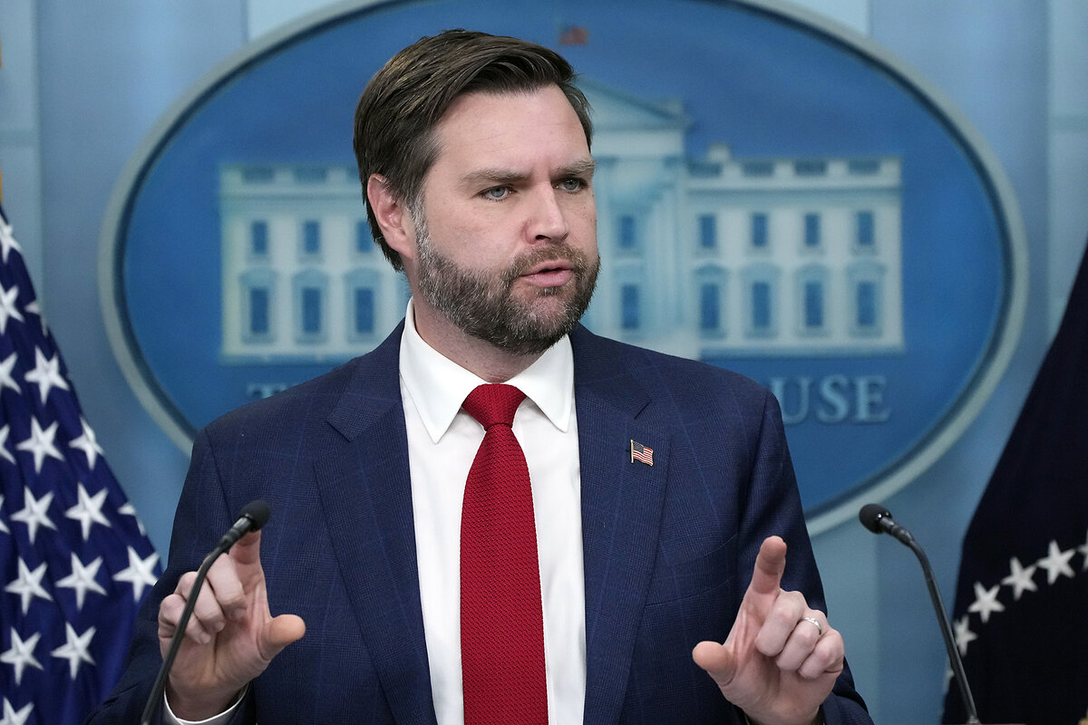 JD Vance speaks in the James Brady Press Briefing Room, with flags and an image of the White House behind him.