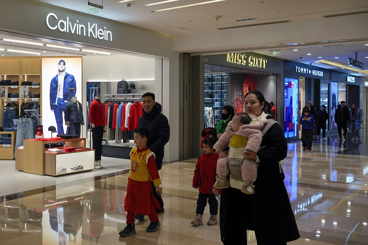 Shoppers walk past glass windows of a Calvin Klein shop in a mall in Beijing, China.