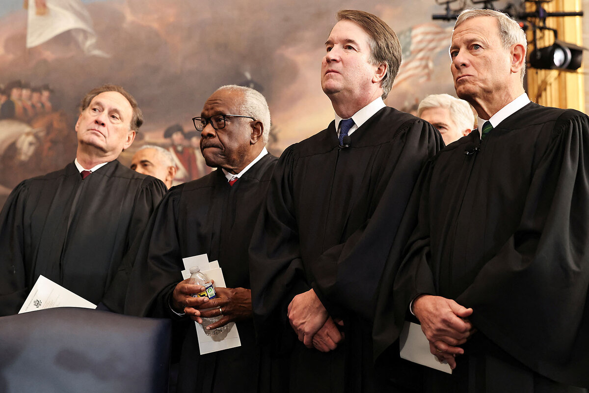 U.S. Supreme Court Justices (from left) Samuel Alito, Clarence Thomas, and Brett Kavanaugh and Chief Justice John Roberts stand together in their black robes.