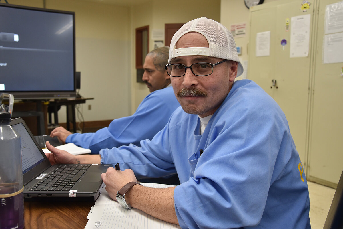Pelican Bay State Prison student Steve Corotan looks at the camera while sitting in front of a laptop in a classroom.