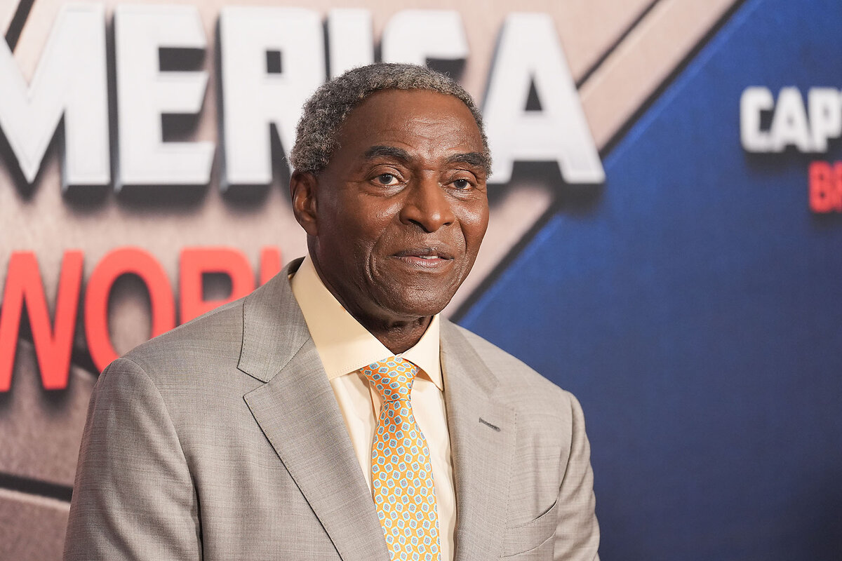 Actor Carl Lumbly stands in front of a 'Captain America: Brave New World' sign at the premiere of the new film.