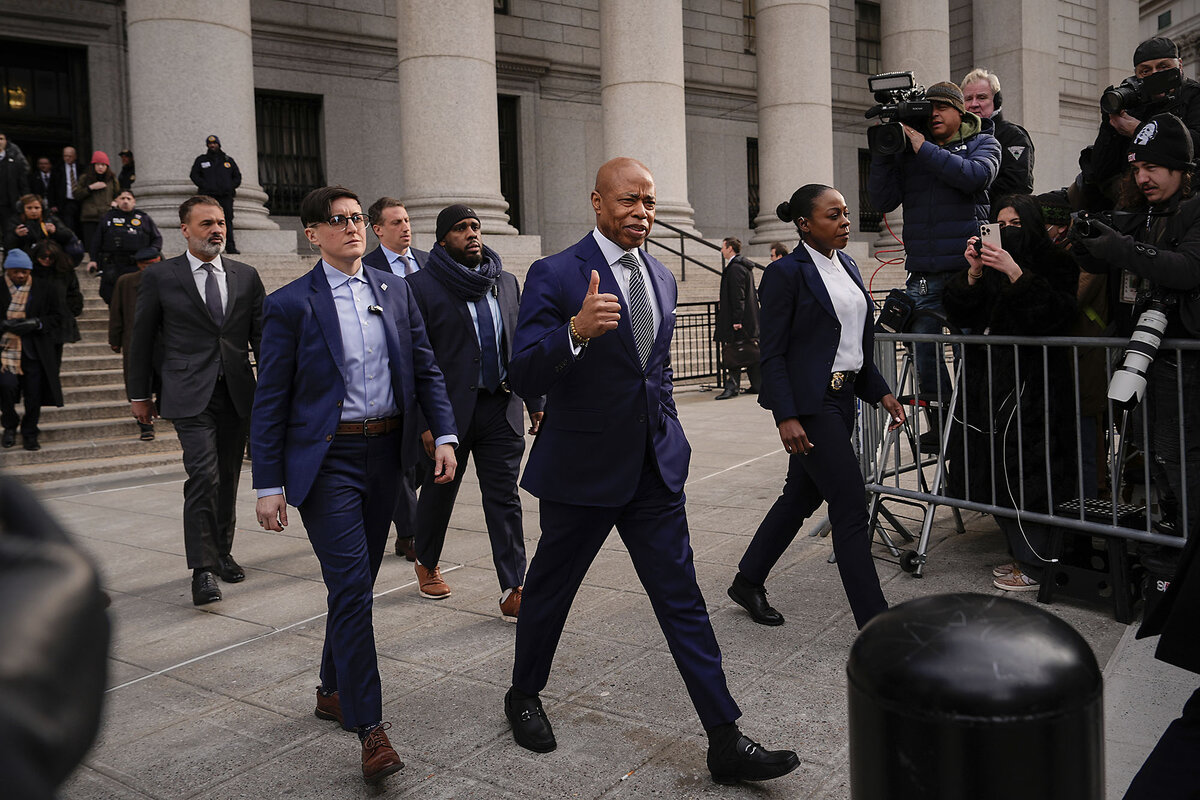 New York Mayor Eric Adams, in a dark suit, strides away from a courthouse's steps. 