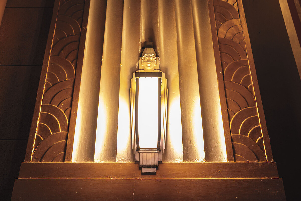 An gold-colored art deco lighting fixture resembles an Egyptian sarcophagus.