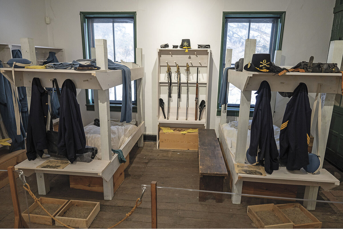 Civil War-era uniforms and weapons are displayed on white shelves.