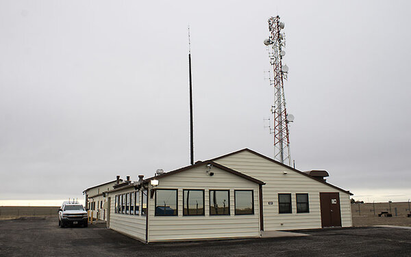 An unassuming house sits on the Nebraska plains with a communications tower rising above.