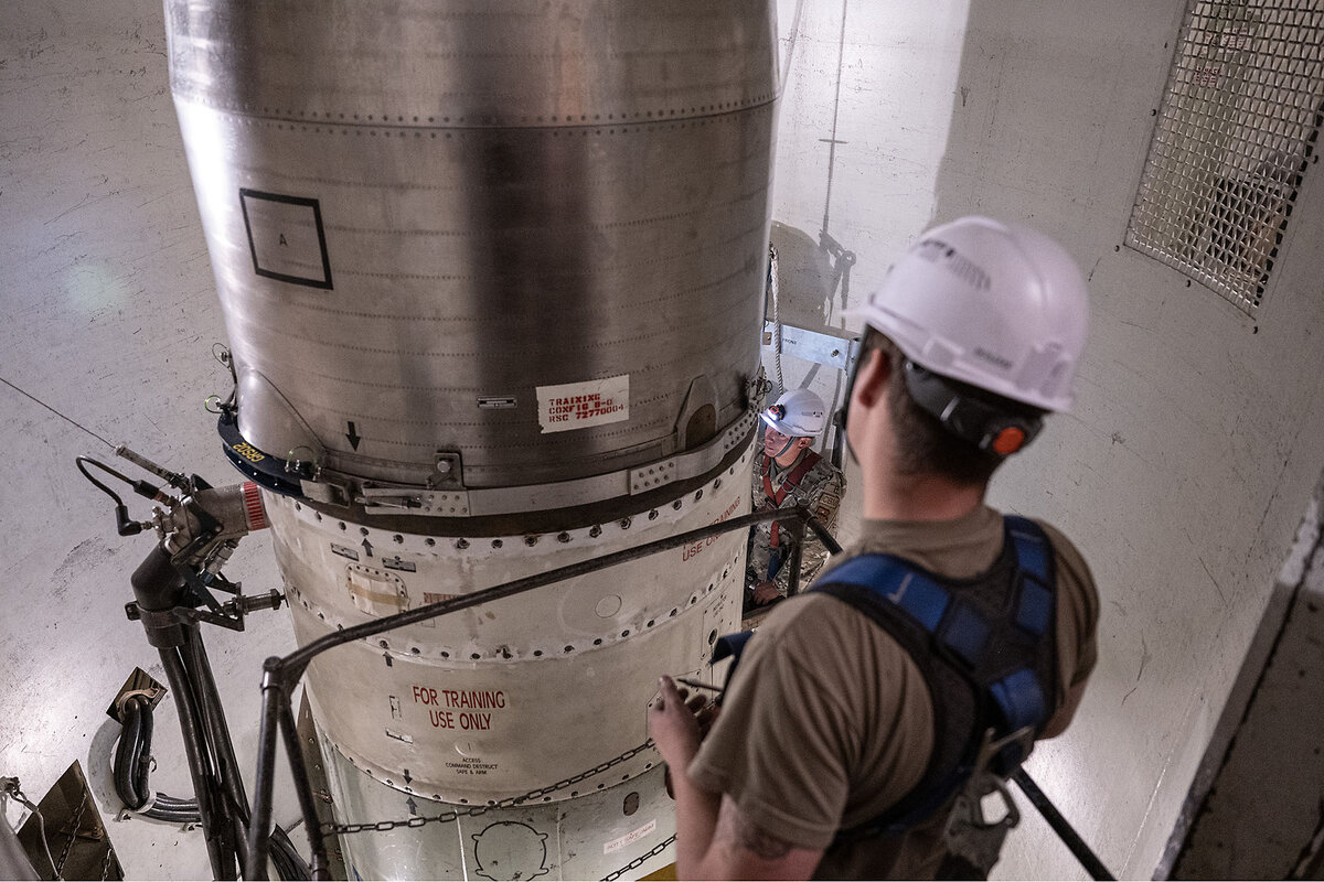 Air Force maintainers wearing hard hats examine a missile labeled 'for training use only.'