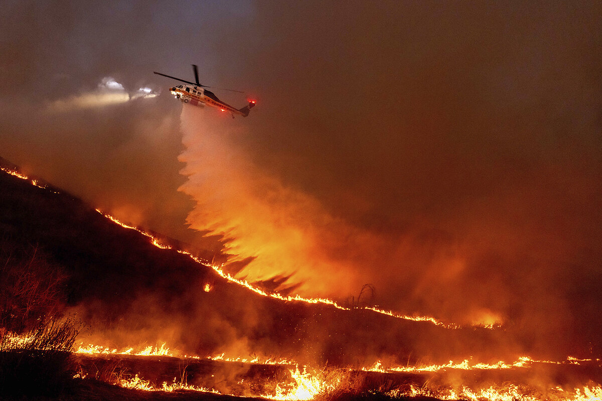A helicopter drops water onto flames of the Kenneth Fire, one of several wildfires in Los Angeles in January 2025.