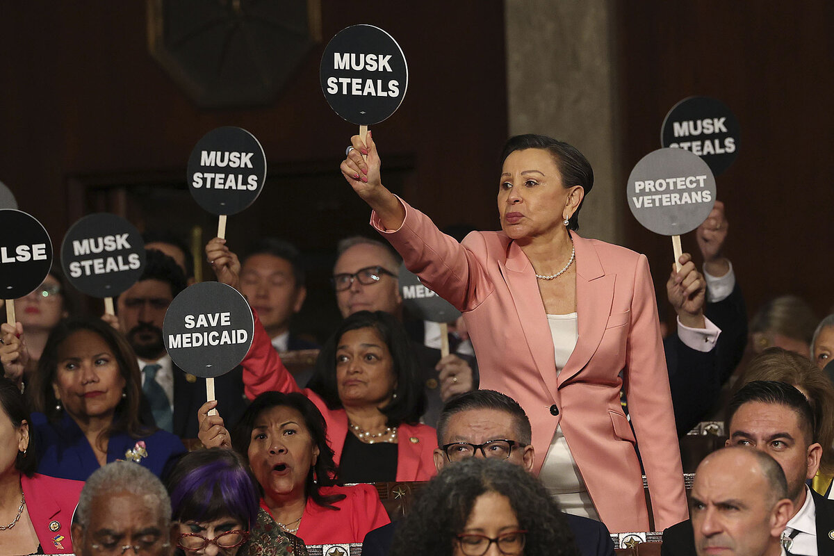 Rep. Nydia Velazquez stands and holds a sign that says ‘Musk steals,’ as other Democratic lawmakers also hold protest signs.