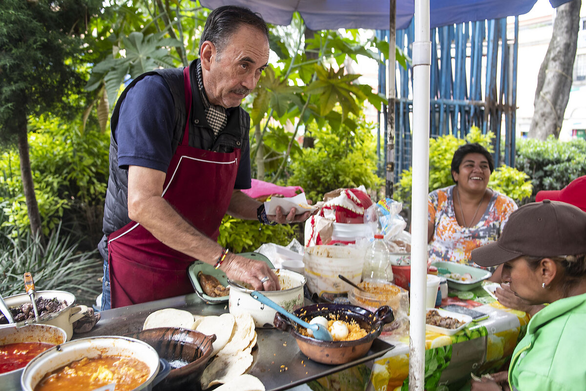 A vendor wears an apron as he serves food outside.