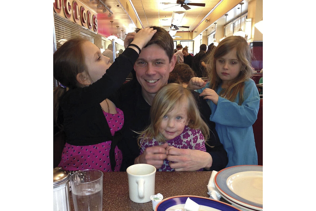 The writer sits at a diner table surrounded by his three young daughters. 