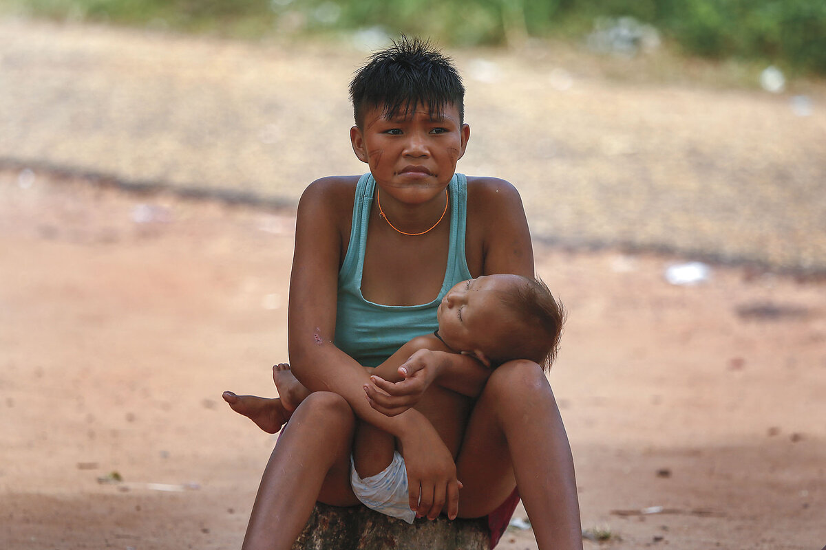 A Yanomami woman sits with her baby outside a health center that supports Indigenous people, in Boa Vista, Brazil.
