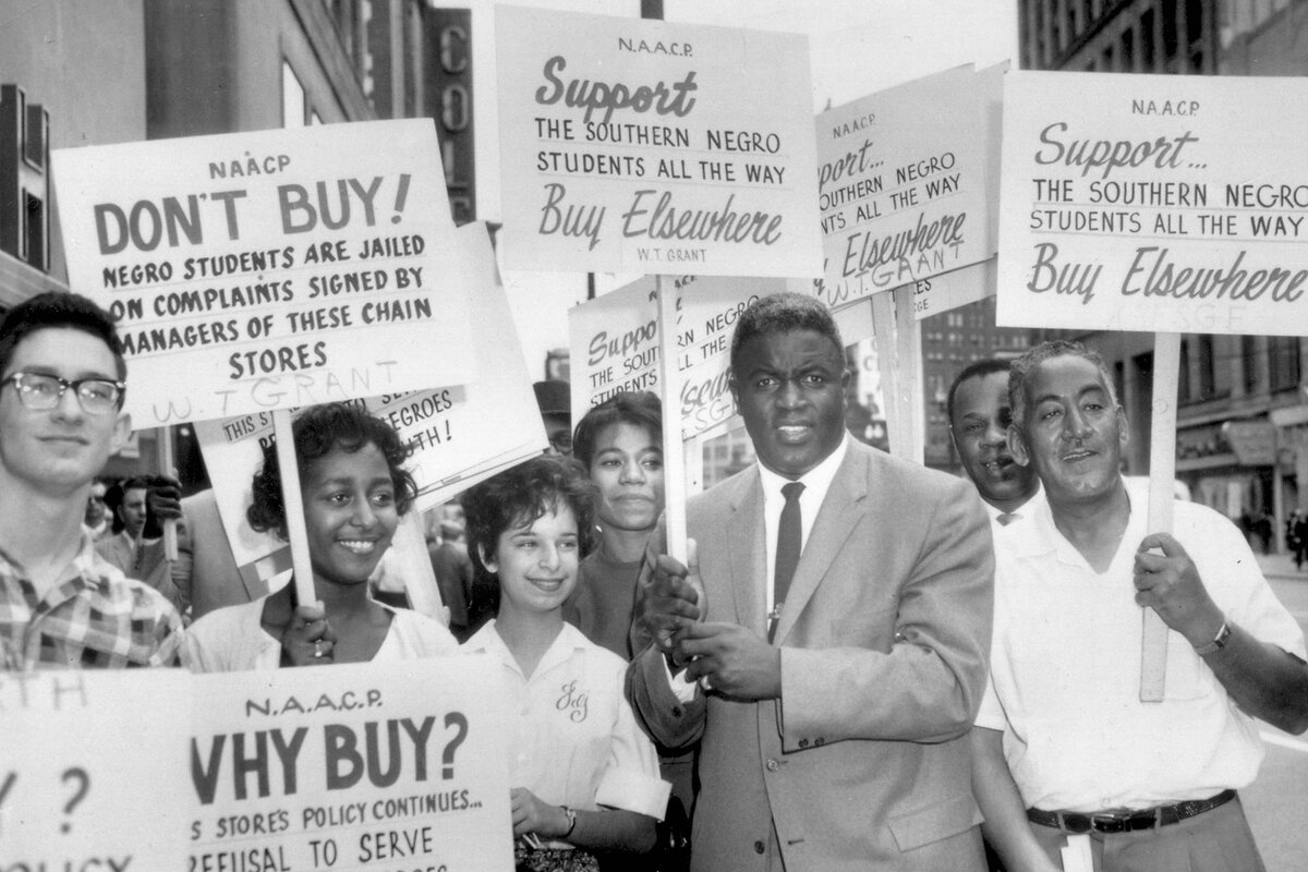 Jackie Robinson holds a sign as he joins a picket line to protest discrimination in Cleveland in 1960