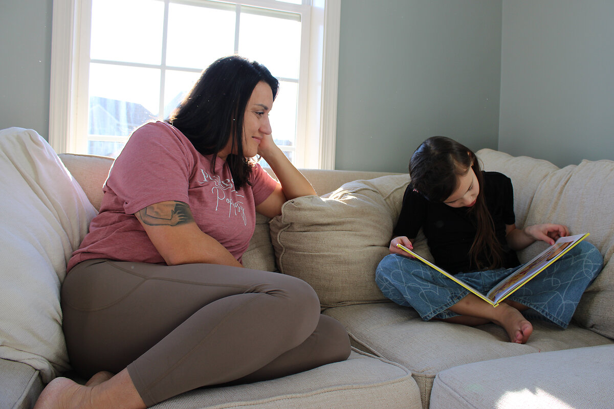 Deanna Linden sits on a couch in her West Virginia home watching her daughter, Rhett, sound out a word 