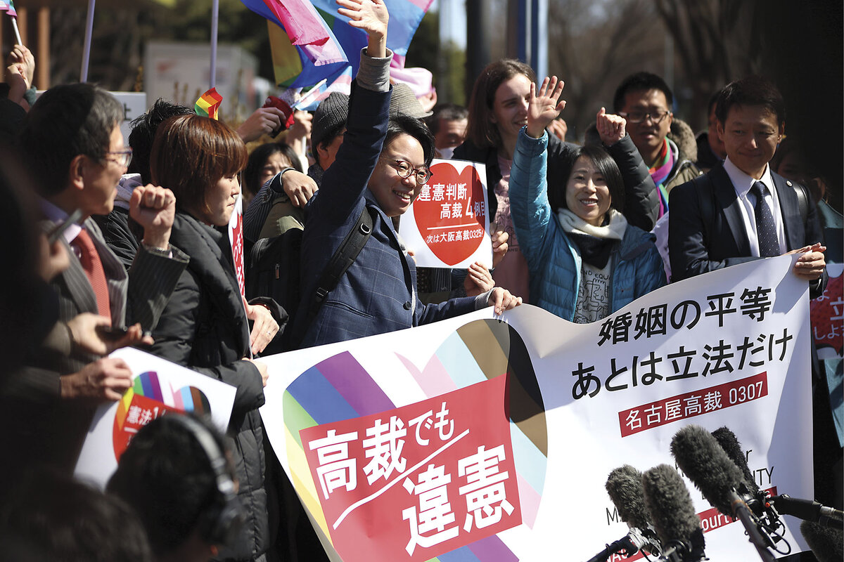 Outside Nagoya High Court in Japan, people waving and holding signs learn of the decision in support of same-sex couples.