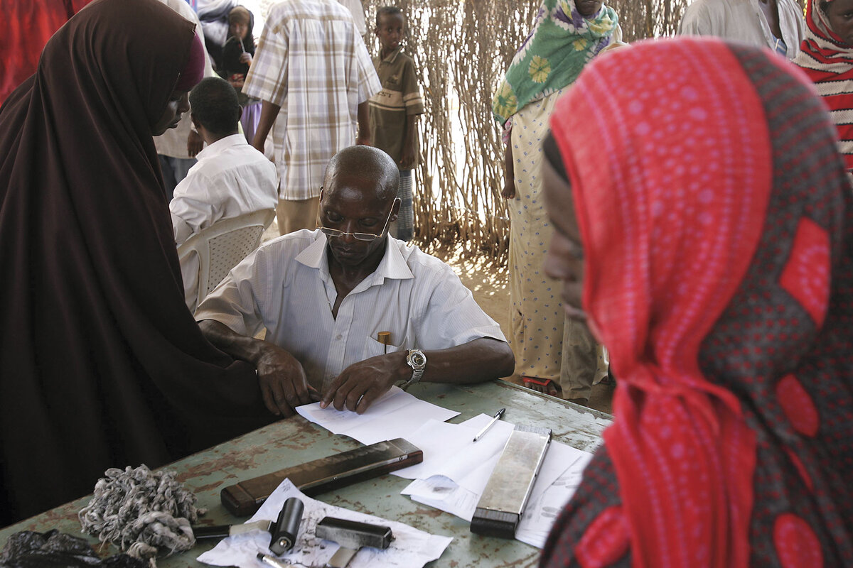 A Somali woman wearing a brown abaya is fingerprinted at the Liboi transit point in Kenya before moving on to a refugee camp.