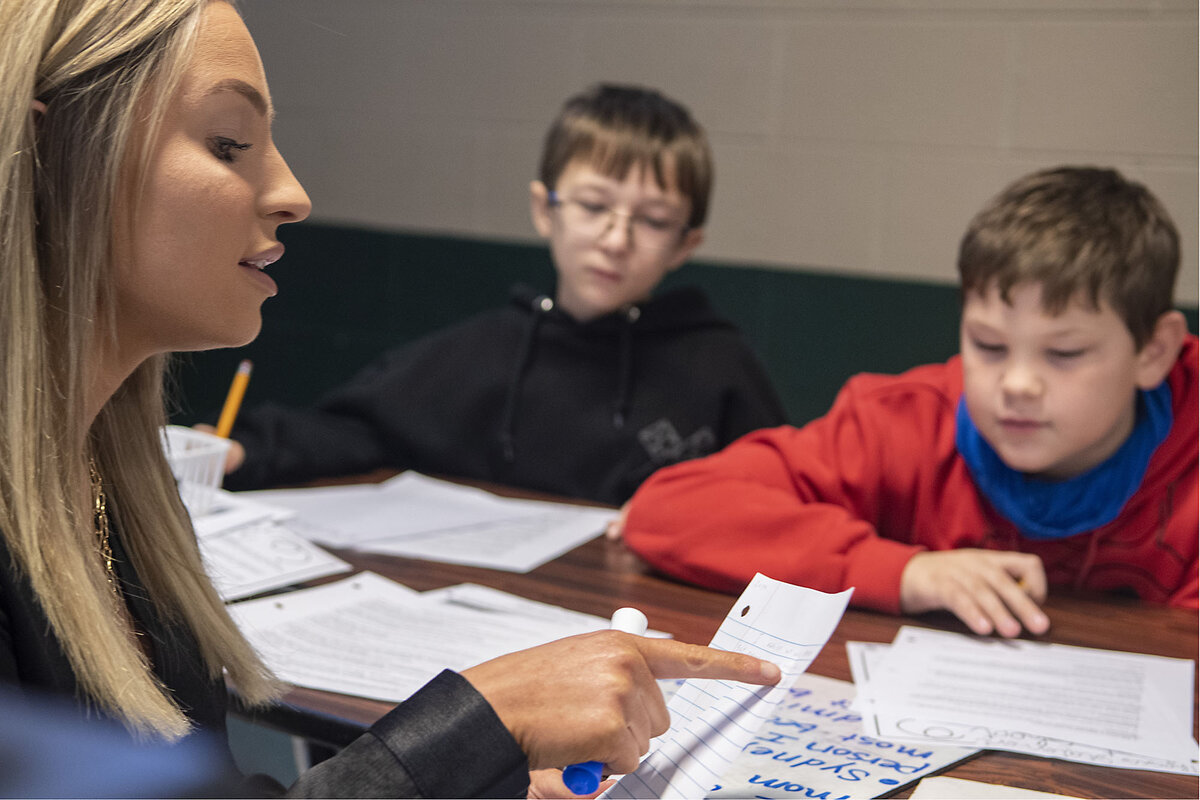 A tutor talks with two young students.