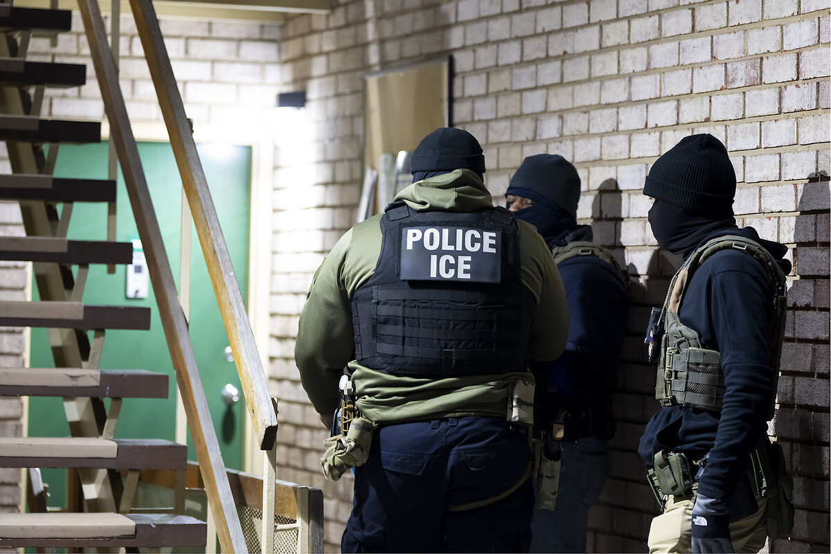 Masked officers wait at the bottom of an indoor staircase.