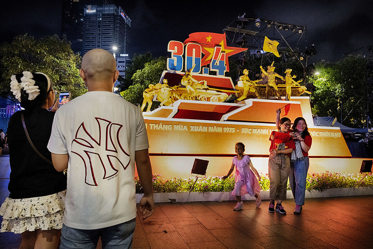 People take photos of a brightly lit display in Vietnam to commemorate of the end of the Vietnam War.