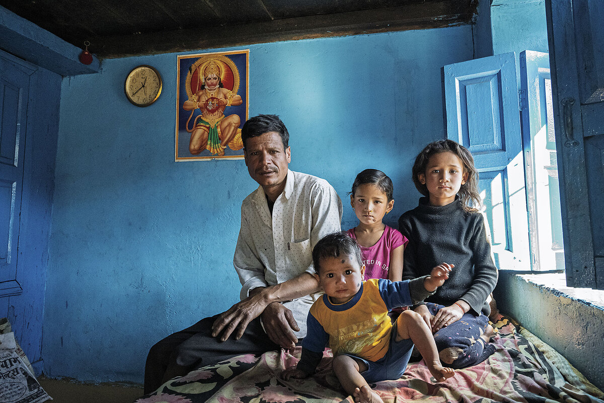 A father poses with three young children.
