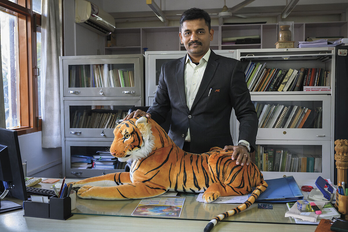 A man in a suit poses with a stuffed tiger.