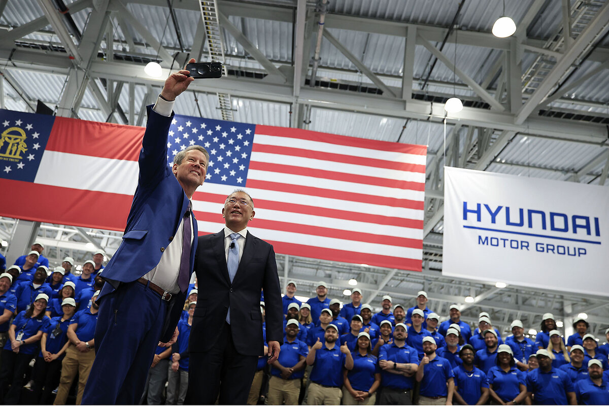 Georgia Gov. Brian Kemp (left) takes a selfie with Euisun Chung, executive chair of Hyundai Motor Group, in front of an American flag.