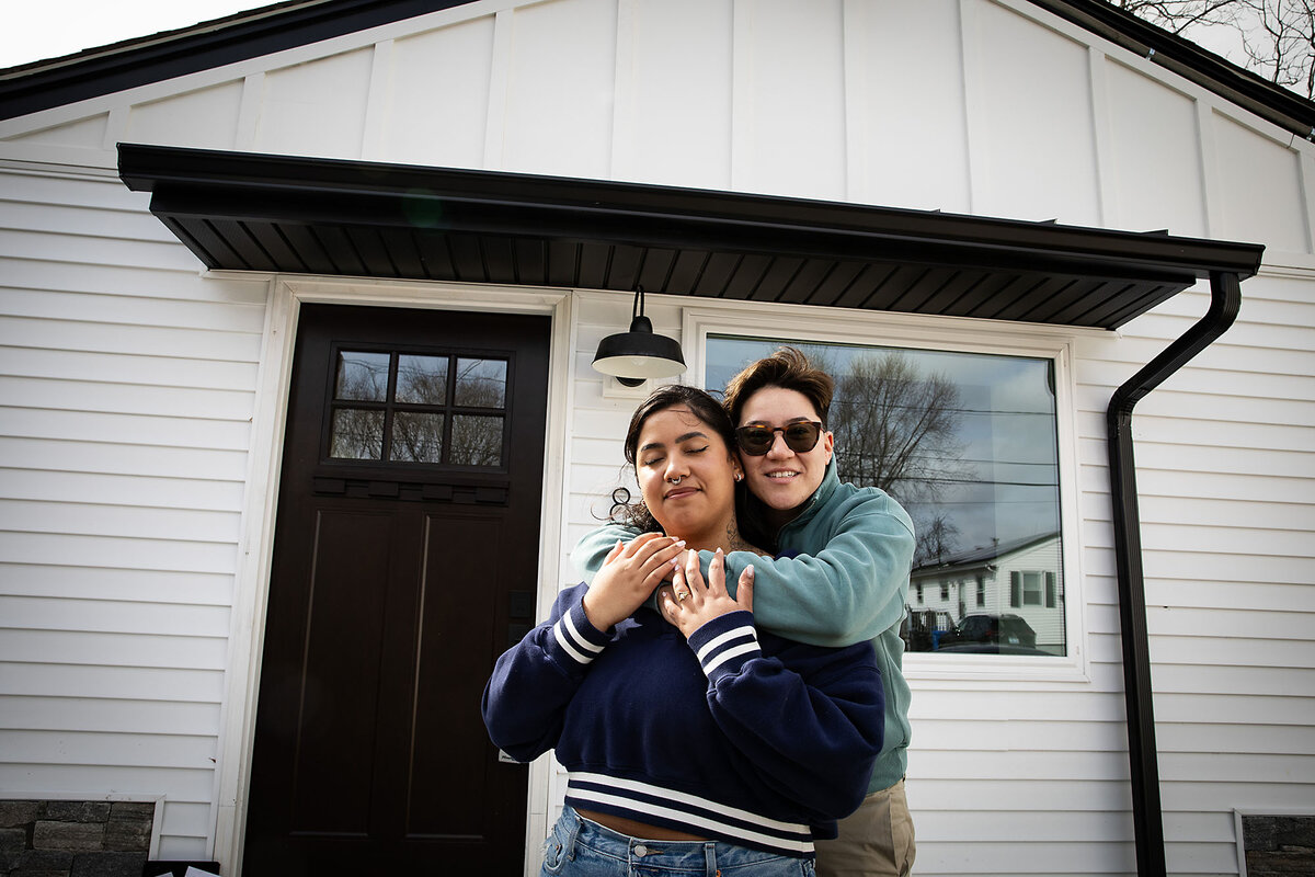 Iliana Damascena hugs her new wife, Yara, in front of the door to their new home in Cranston, Rhode Island.