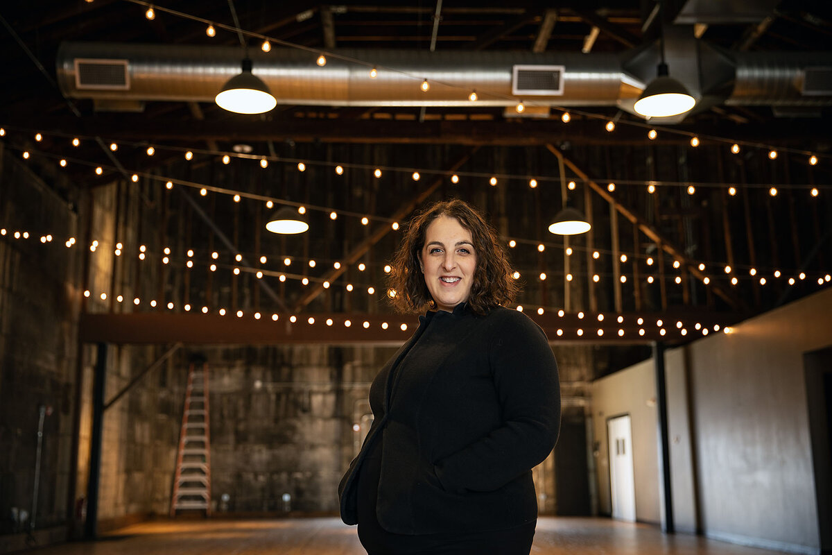 Sarah Narcus stands amid strings of Edison lights in her event space, Olio, in Peabody, Massachusetts.