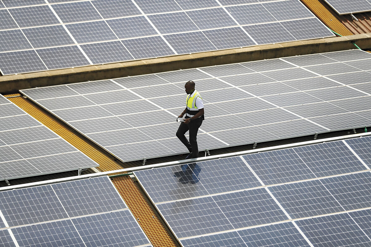 A technician examines solar panels on the roof of a company in Nairobi, Kenya.
