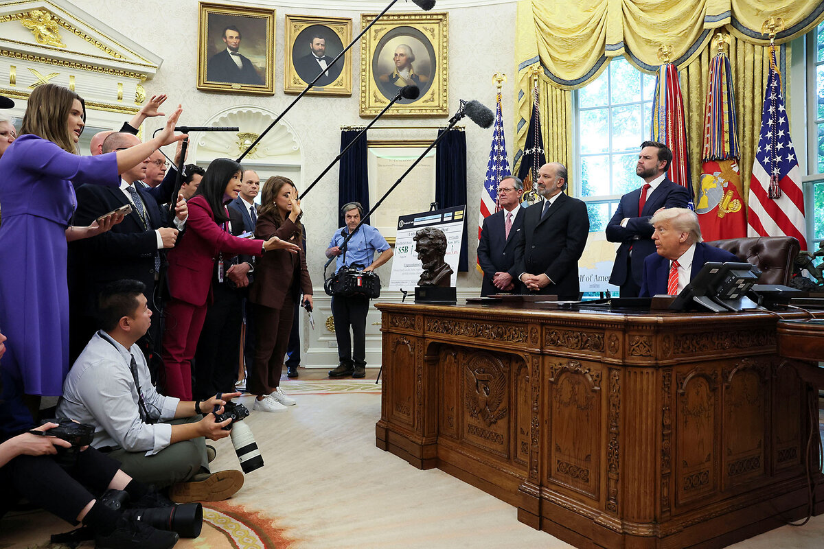 President Donald Trump sits behind his desk, facing a bank of reporters in the White House Oval Office in Washington.