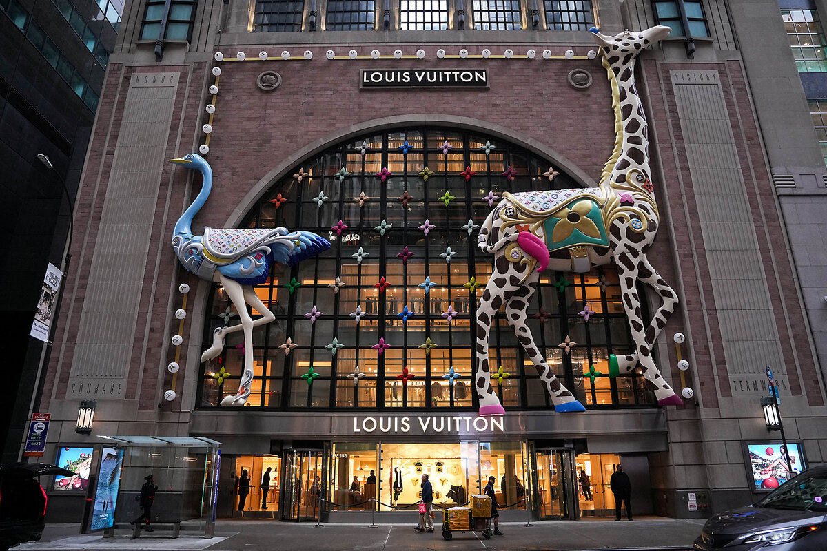 People walk past a Louis Vuitton store in New York City, where prices may rise due to proposed tariffs on European imports..
