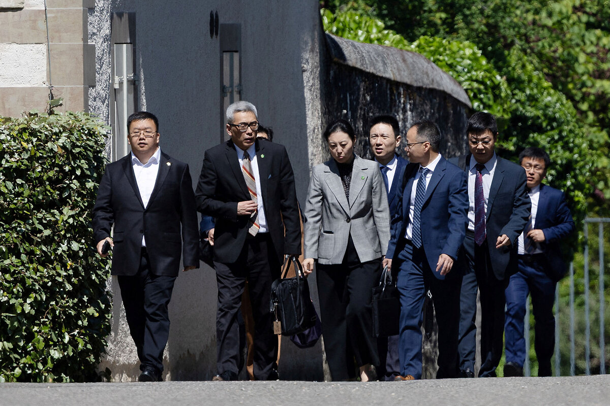Members of the Chinese trade-talks delegation leave a building and walk in a group, talking amongst themselves.