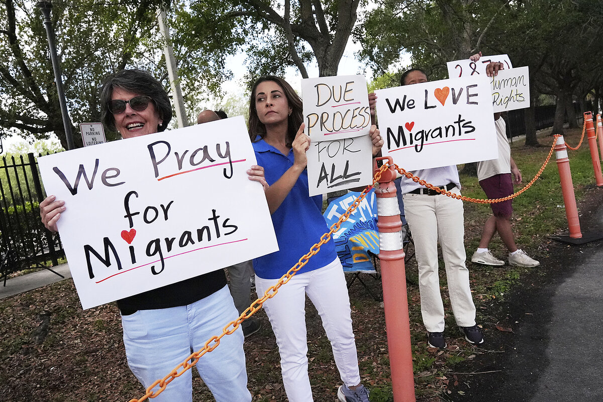 People with signs saying 'We love migrants' stand together outside the South Florida office of U.S. Immigration.