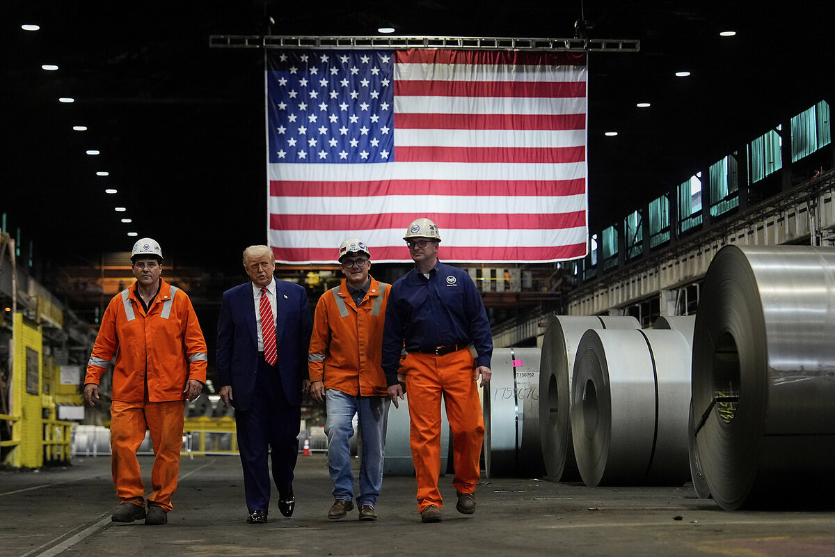 President Donald Trump walks with workers past coils of flat-rolled steel, with a U.S. flag hanging behind them in the factory.