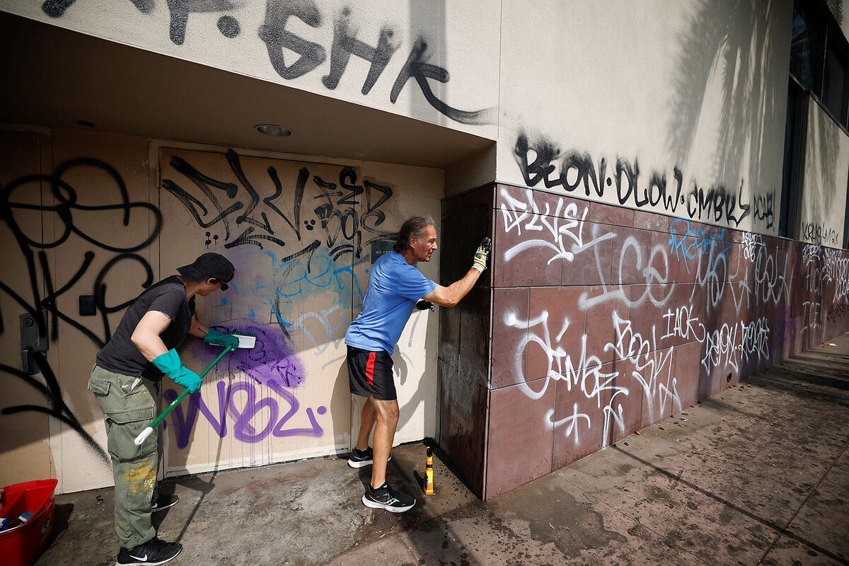 Two people scrub walls to remove graffiti after days of protests against federal immigration sweeps left their mark.