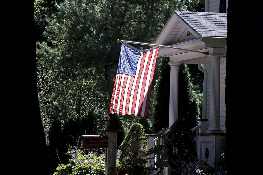 An American flag is backlit by the sun as it hangs outside a house in Hingham, Massachusetts.