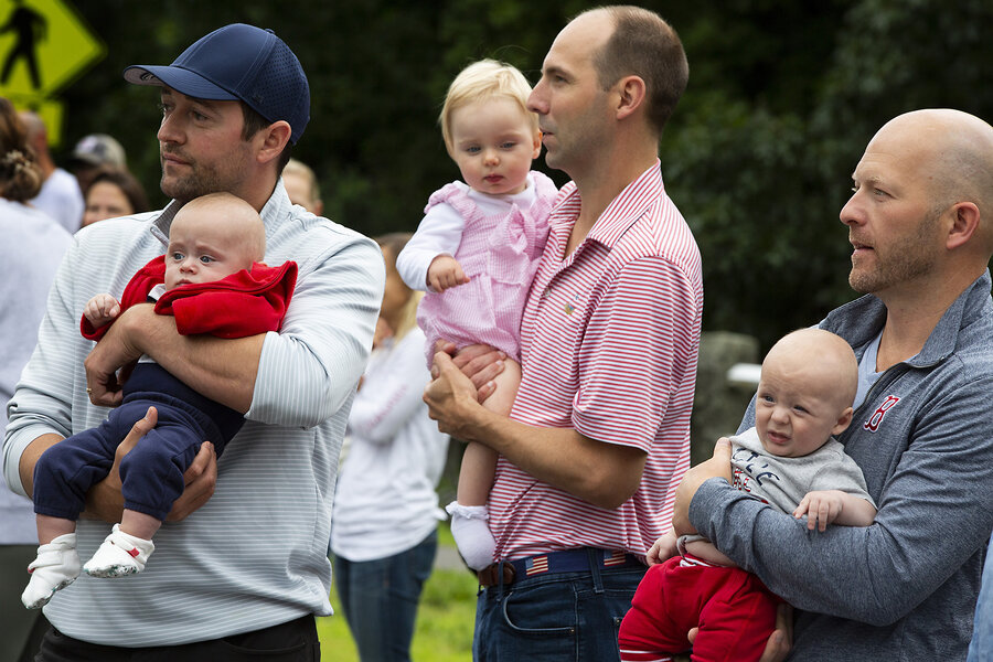Fathers hold their babies at a Fourth of July parade in 2021 in Hingham, Massachusetts. A movement to encourage people to have more children has made its way into the Trump administration's budget bill now under consideration. 