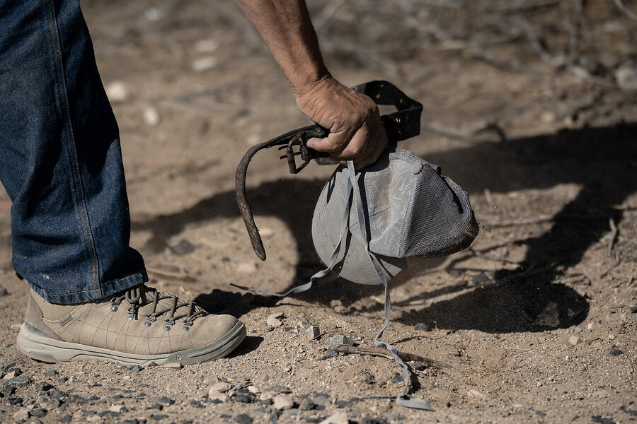 Robert Ardovino picks up a hat, belt, and shoelaces, all presumed to be left there by migrants who crossed the U.S.-Mexico border, on his property May 1, 2025, in Sunland Park, New Mexico. 