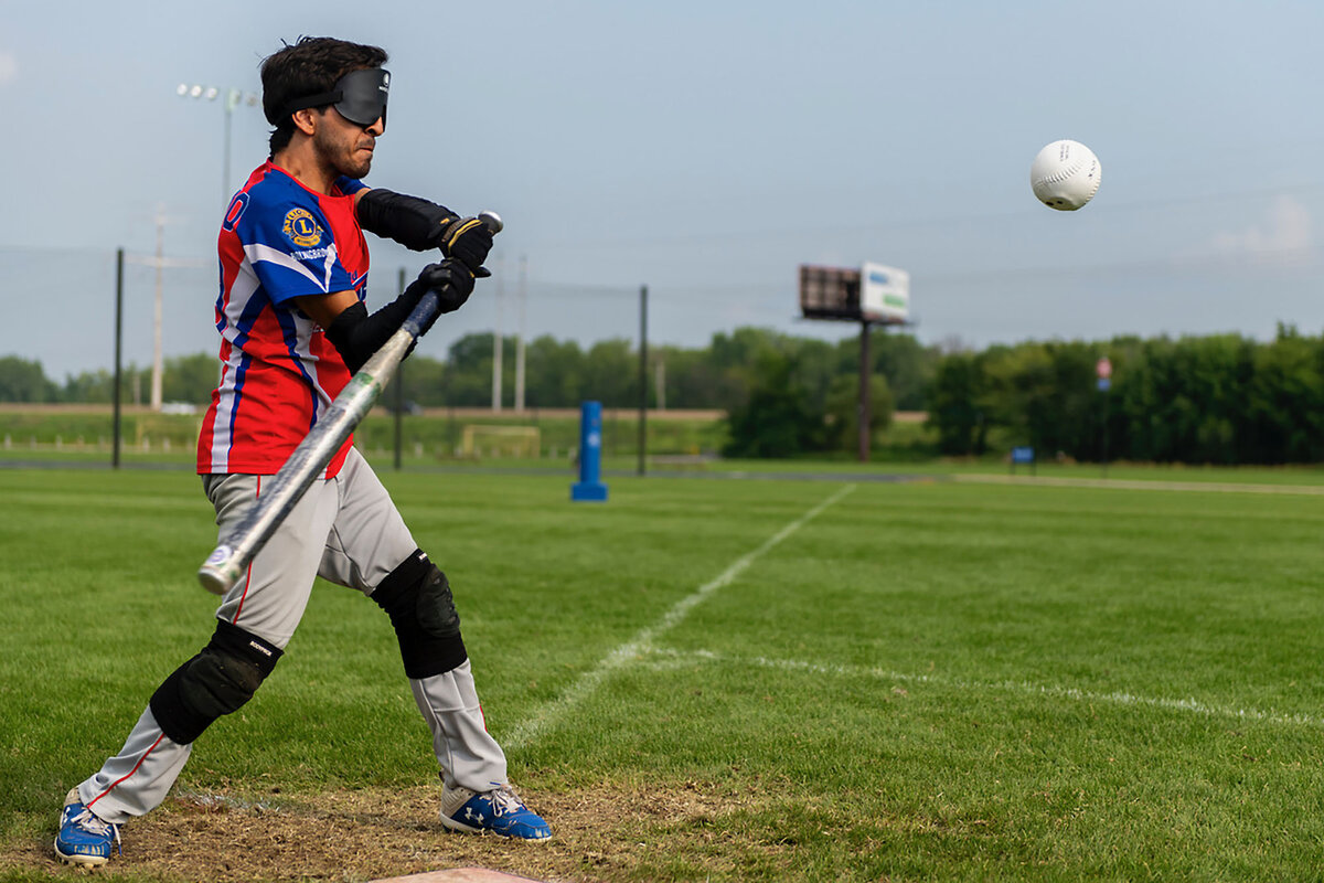 Chicago Comet Alex Gamino holds a bat as a ball sails near him at the 2024 Beep Baseball World Series.
