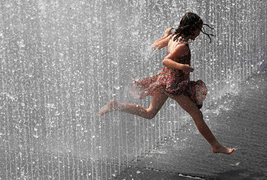 17. A girl plays in a fountain on a summer's day in London. 