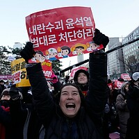 A crowd celebrates after hearing that South Korea's parliament voted to impeach President Yoon Suk Yeol, outside the National Assembly in Seoul, Dec. 14, 2024. The signs read, 