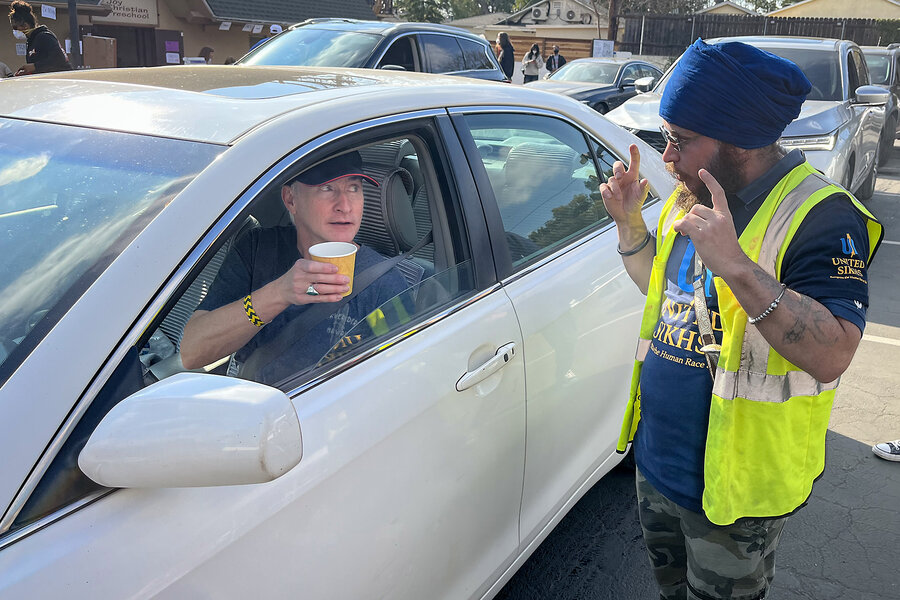 Sikh Gyan Singh hands a cup of chai to a fire evacuee in a car.